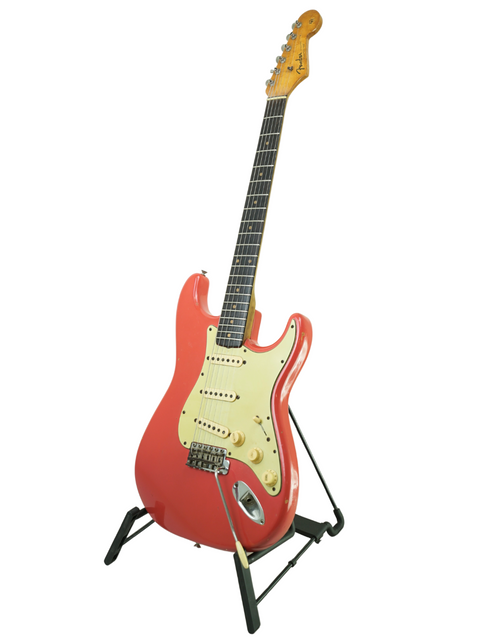 A striking red Fender Stratocaster guitar from 1963, displayed on a stand, featuring the unique Fiesta Red color associated with Phil Emmanuel.