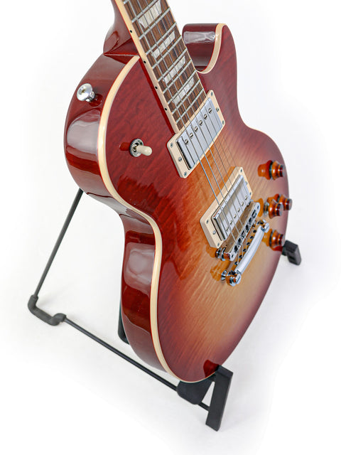 A striking red Gibson Les Paul Standard guitar displayed on a stand, set against a bright white background for a bold look.