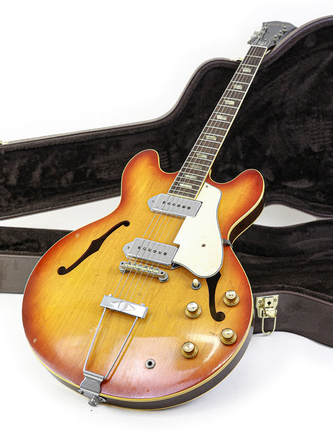 A sunburst electric guitar, the 1965 Epiphone Casino, accompanied by its vintage case.
