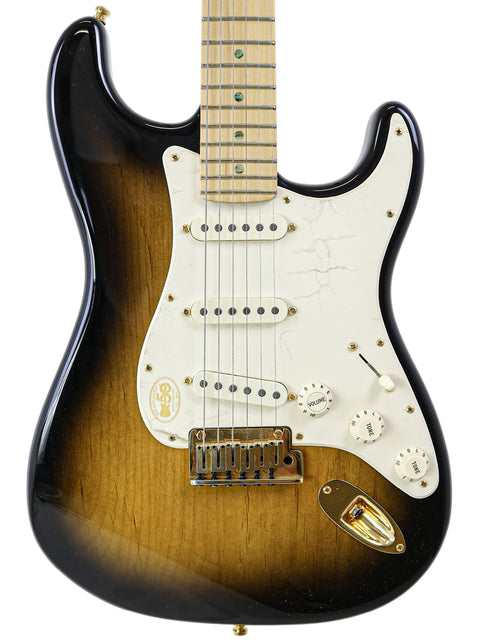 A sunburst electric guitar with a white pickguard and maple fretboard.