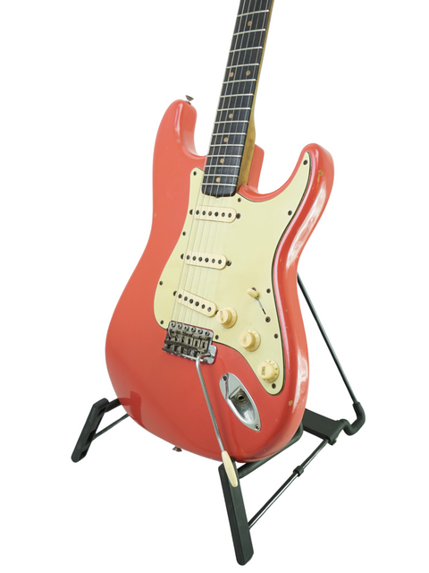 A vintage 1963 Fender Stratocaster in Fiesta Red displayed on a stand, highlighting its iconic electric guitar design.