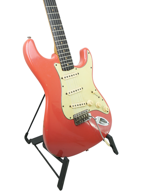 A vintage 1963 Fender Stratocaster in Fiesta Red, elegantly displayed on a stand, highlighting its electric guitar features.
