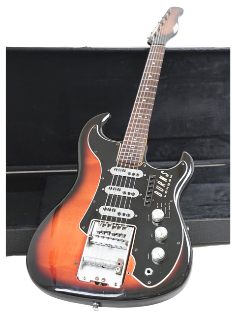 A vintage 1964 Burns Split Sound guitar resting in its case, contrasted beautifully against a deep black background.