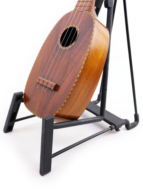 A vintage Kamaka Pineapple Style #3 ukulele, circa 1928, positioned on a stand, emphasizing its historical significance.
