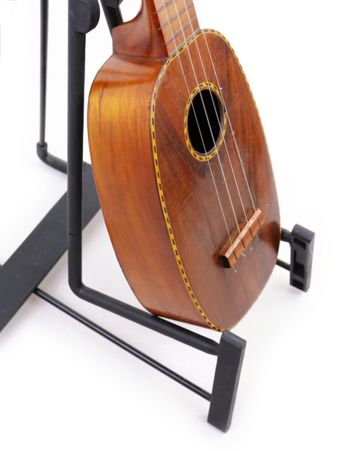 A vintage Kamaka Pineapple Style #3 ukulele from 1928 sits on a stand, illustrating its timeless appeal and craftsmanship.