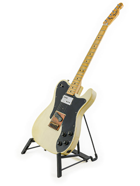 A white Fender Telecaster Custom guitar from 1978 on a stand, featuring a sleek black pick guard.
