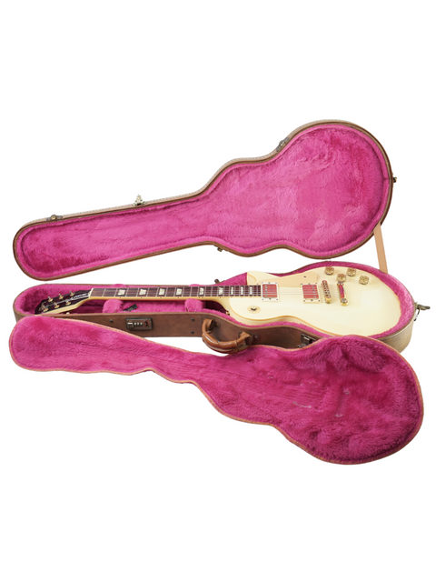 A white guitar case with pink lining containing a pink vintage Gibson Les Paul Standard from 1989, Arctic White finish.
