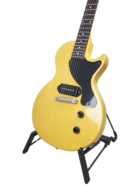 A yellow Gibson Custom Les Paul Jr. electric guitar on a stand, highlighting its unique color and classic design.