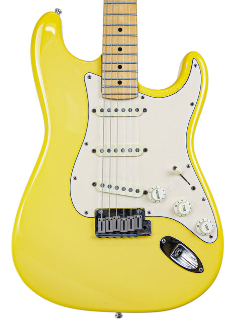 A yellow electric guitar with a white pickguard and maple neck isolated on a white background.