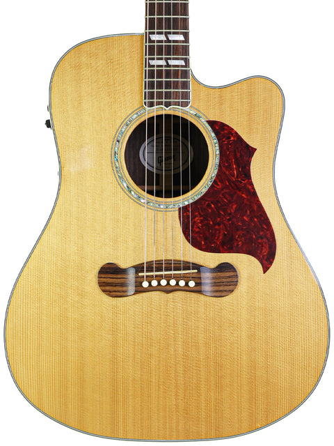 An acoustic guitar with a wooden body and red pickguard, model Gibson Songwriter Studio Deluxe EC -USA 2014.
