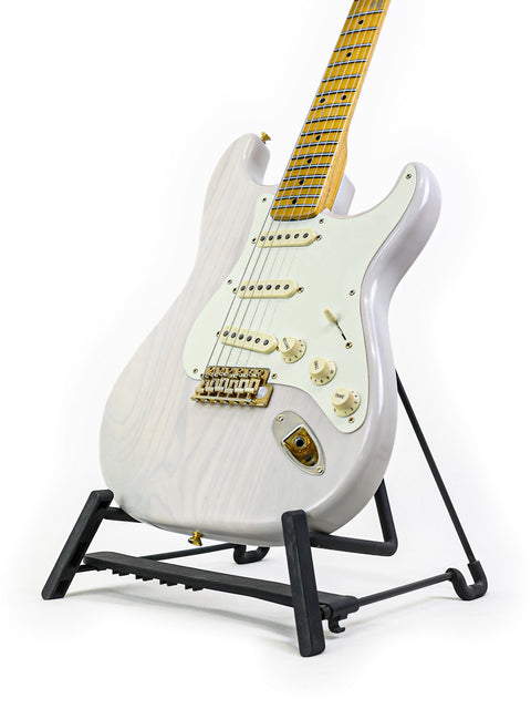 An electric guitar with a white finish and maple neck on a black stand, isolated on a white background.