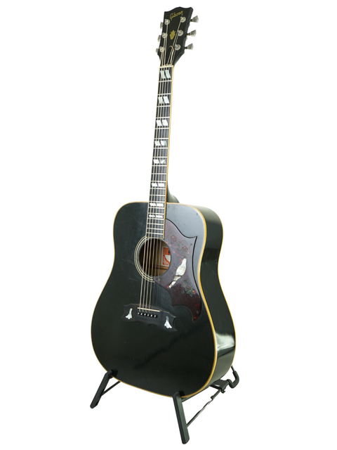 Black 1977 Gibson Dove Custom acoustic guitar resting on a stand, showcasing its vintage charm.