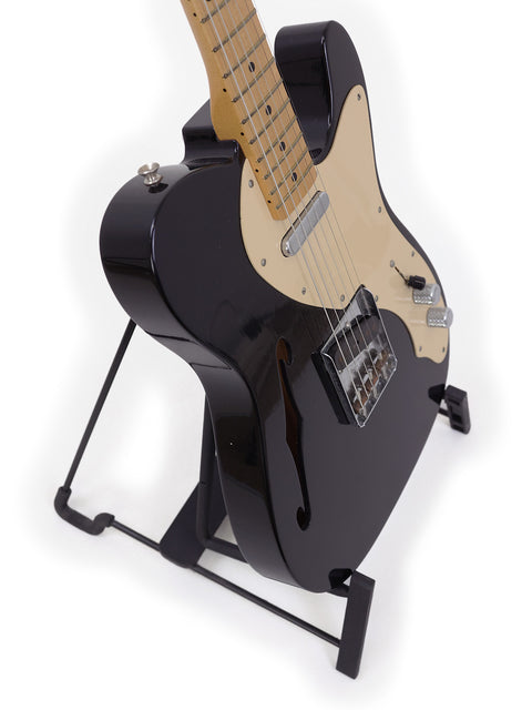 Black Fender Custom Shop Telecaster Thinline guitar displayed on a stand with a bright white backdrop.
