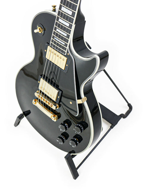 Black Gibson Les Paul Custom electric guitar on a stand, showcasing its sleek design and craftsmanship from the USA, 2010.