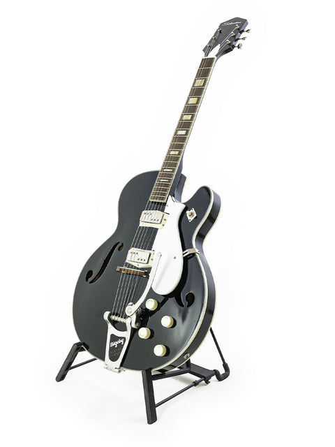 Black Silvertone 1446 guitar on a stand, highlighting its vintage charm against a bright white backdrop.