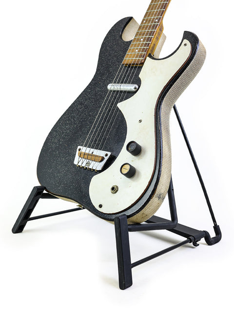 Black and white vintage Harmony Silvertone 1448 guitar on a stand, highlighting the 'Amp-in-Case' feature from the 1960s.