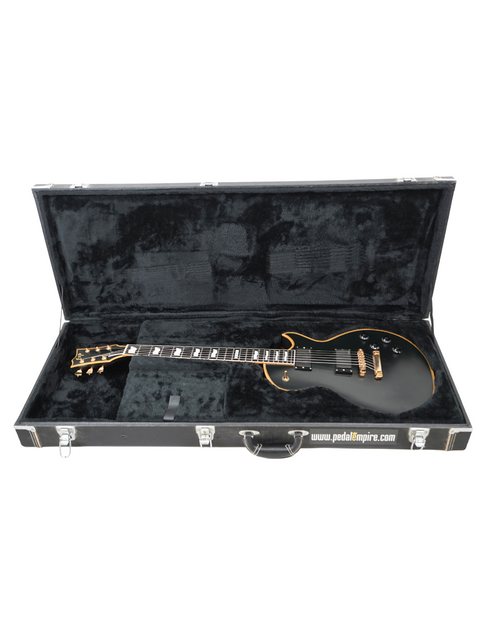 Black electric guitar with gold accents in an open case.