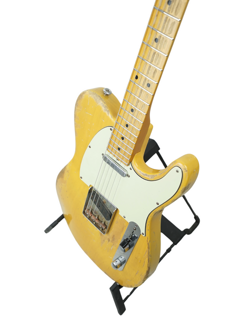 Bright yellow Suhr Classic T guitar with a black stand, featuring a beautifully aged finish from 2015.