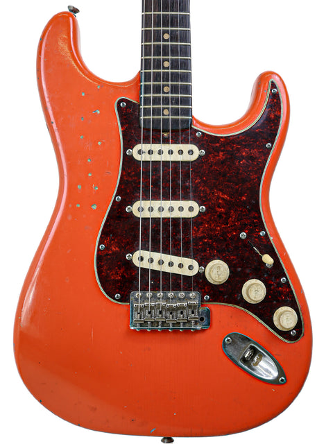 Classic 1963 Fender Stratocaster in vibrant orange with a stylish black pickguard, a true vintage gem.