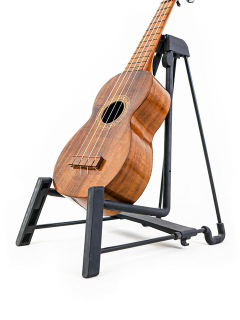 Close-up angled view of the Aloha Tabu Akai ukulele on a stand, highlighting the detailed craftsmanship and glossy finish.

