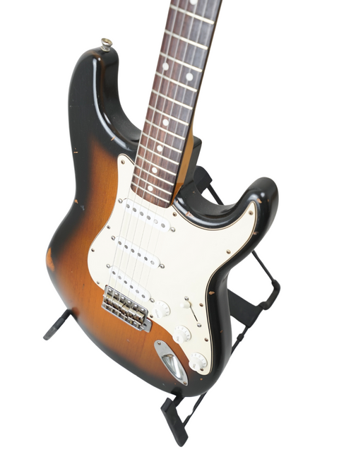 Close-up of a 2009 Nash S63 Stratocaster Relic guitar featuring a sleek black body and a warm brown neck.