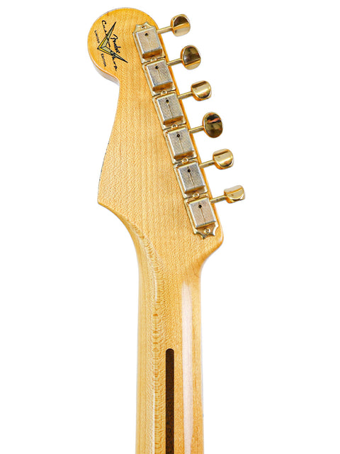Close-up of a Fender guitar headstock with gold tuning pegs against a white background.