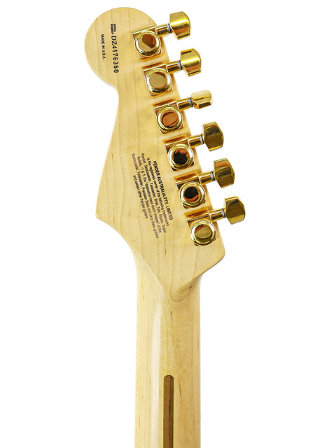 Close-up of a guitar headstock with gold tuning pegs on a white background.