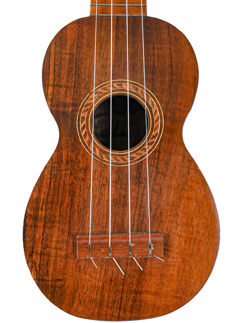 Close-up of the Aloha Tabu Akai ukulele body, featuring detailed rosette design around the soundhole and natural wood grain.

