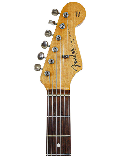 Close-up view of a vintage Fender AVRI ‘62 Stratocaster guitar, focusing on its elegant wooden headstock and vintage vibe.

