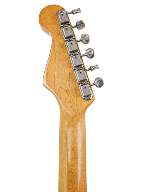 Detailed view of a vintage Fender AVRI ‘62 Stratocaster guitar head, highlighting the wooden body and iconic craftsmanship.