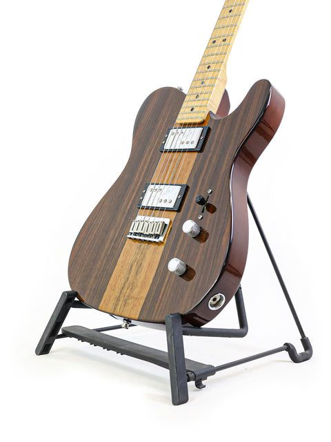 Electric guitar on stand with wood finish and white pickguard.