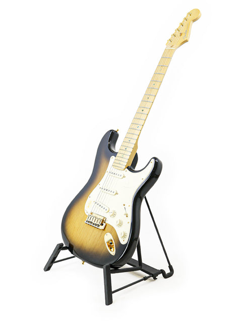 Electric guitar with sunburst finish on stand against white background.