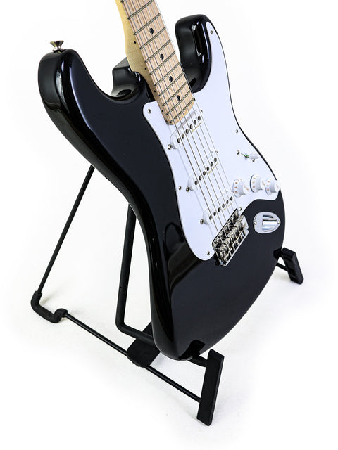 Fender Eric Clapton "Blackie" Stratocaster, a black electric guitar on a stand, set against a white background.