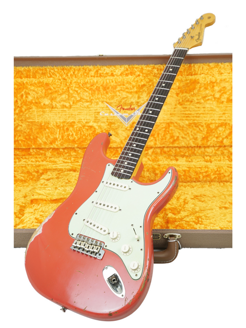 Fender Kyle McMillin Masterbuilt 1960 Stratocaster Relic guitar in red, resting in its case on a white surface.

