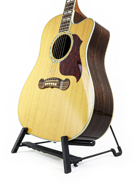 Gibson Songwriter Studio Deluxe EC guitar displayed on a stand, set against a simple white backdrop, highlighting its features.