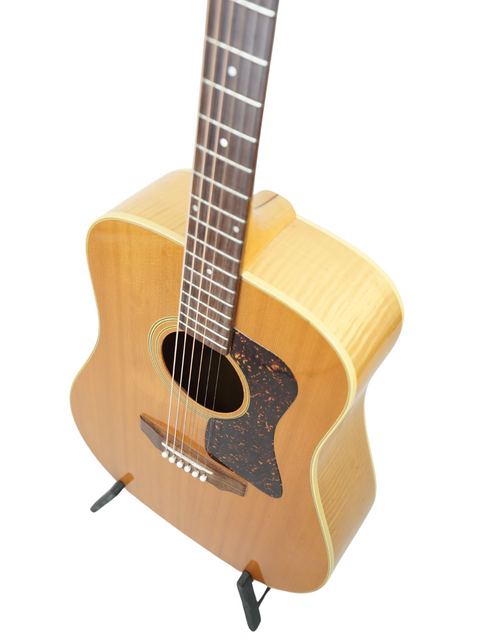 Guild D030A07 Dreadnought guitar on a stand, showcasing its classic design against a clean white background.
