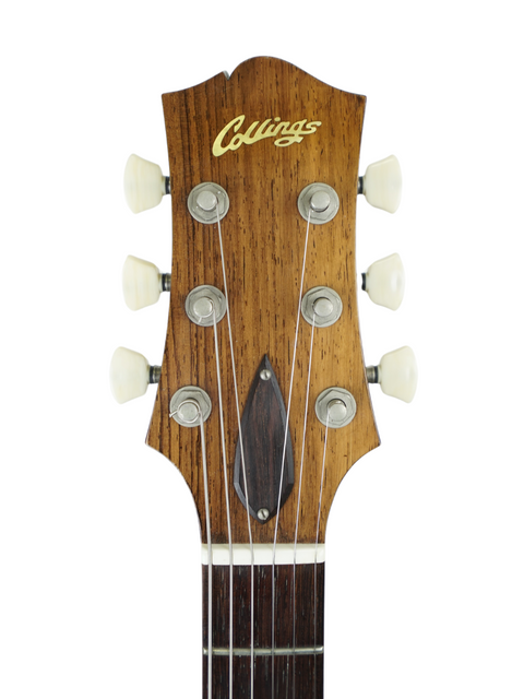 Headstock of a Collings guitar with tuning pegs against a white background.