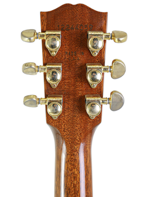 Headstock of a Gibson Songwriter Studio Deluxe EC acoustic guitar featuring brass tuning knobs, showcasing elegant craftsmanship.
