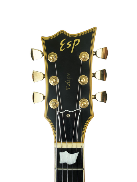 Headstock of a black ESP Eclipse guitar with gold hardware on a white background.