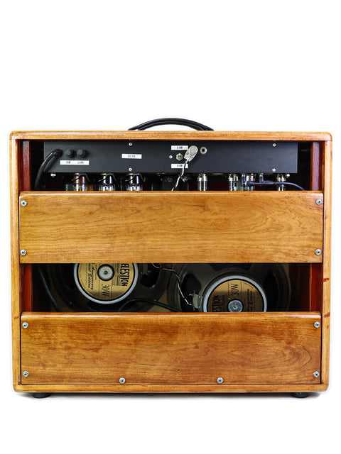 Rear view of an open wooden guitar amplifier cabinet showing speakers and electronics.
