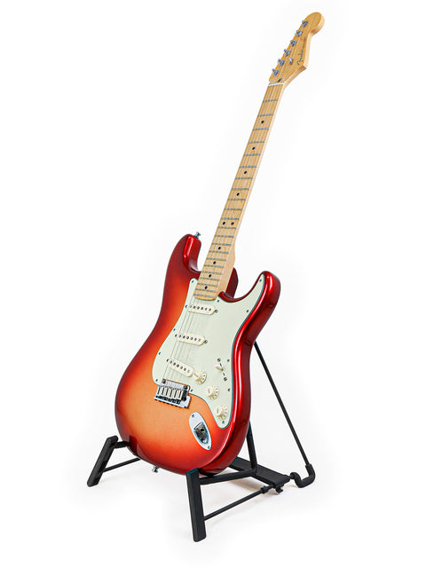 Red and orange electric guitar on a black stand against a white background.