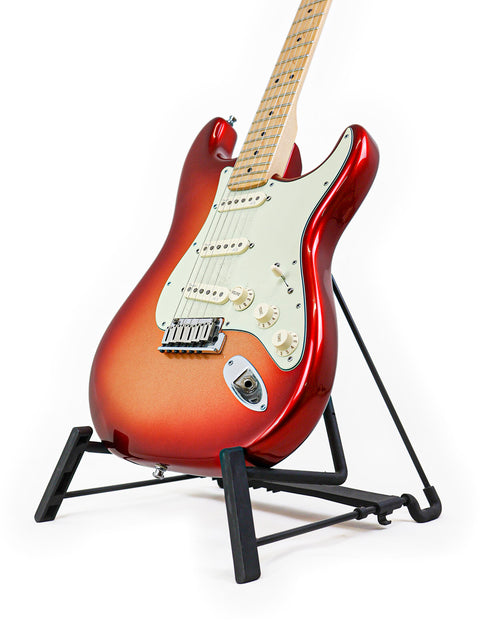 Red electric guitar on a black stand against a white background.