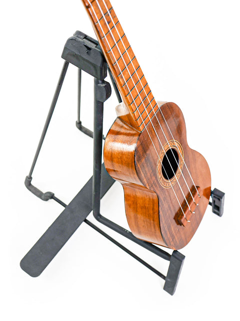 Side angled view of the Aloha Tabu Akai ukulele on a stand, showing its slender profile and vintage Hawaiian build.

