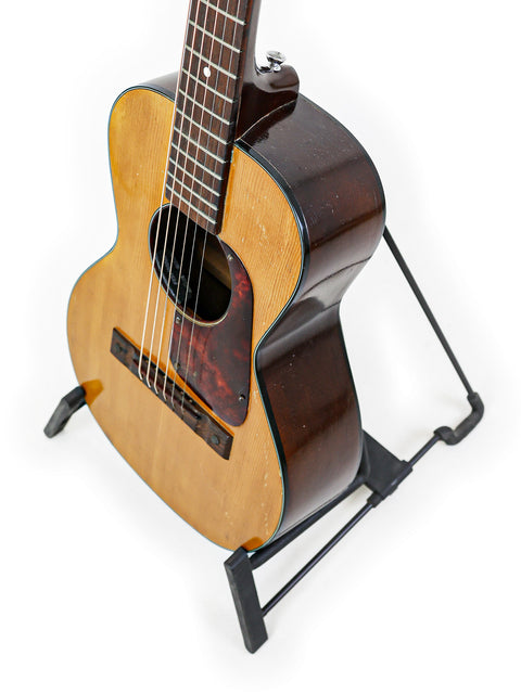 Small Kay K113 Parlour guitar (1966-68) resting on a stand, set against a pristine white background.