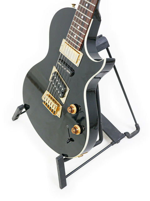 Stunning black electric guitar with a gold headstock on a stand, ideal for players seeking quality and style - Gibson Nighthawk 1999.