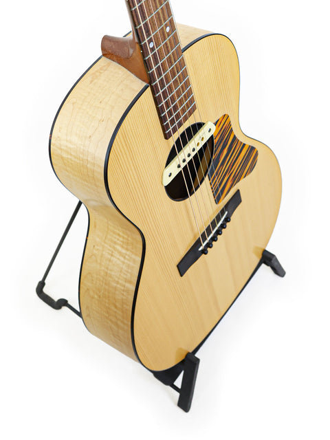The Waterloo WL-14 X Scissortail, a small acoustic guitar, stands proudly on a stand, perfect for music lovers.
