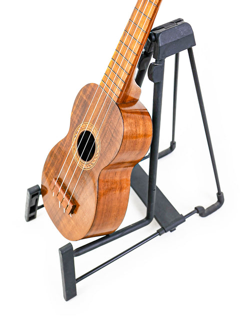 Top-down view of the Aloha Tabu Akai ukulele on a stand, focusing on its unique body shape and fretboard design.

