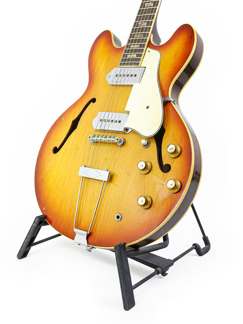 Vintage Epiphone Casino guitar on a stand, set against a clean white background, showcasing its classic design from 1965.
