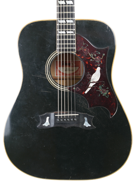 Vintage black acoustic guitar, a 1977 Gibson Dove Custom, with a striking bird design on its back.