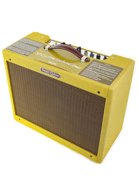 Yellow tweed guitar amplifier with a brown handle and control knobs on top.